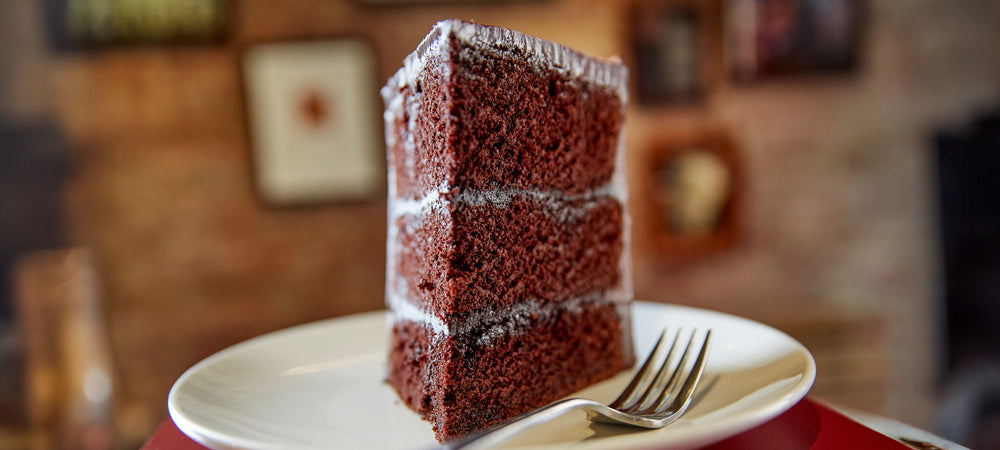 Close up looking into the point of a slice of chocolate layer cake - on a plate with a fork, blurred background