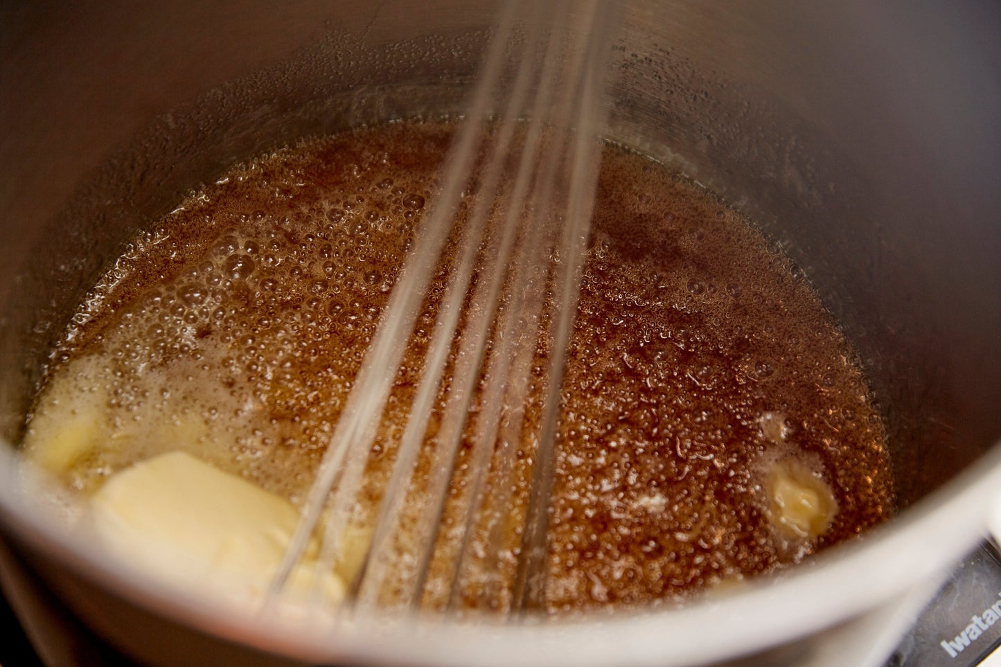 
                  
                    Inside view of a pot where caramel sauce is being prepared. Whisk is in pot with a motion blur
                  
                