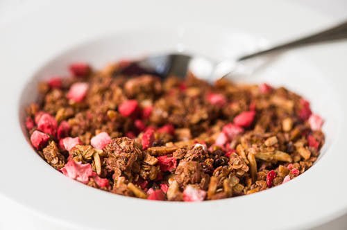 
                  
                    An angled view of the a bowl full of granola. Everything but the granola is out of fucus
                  
                