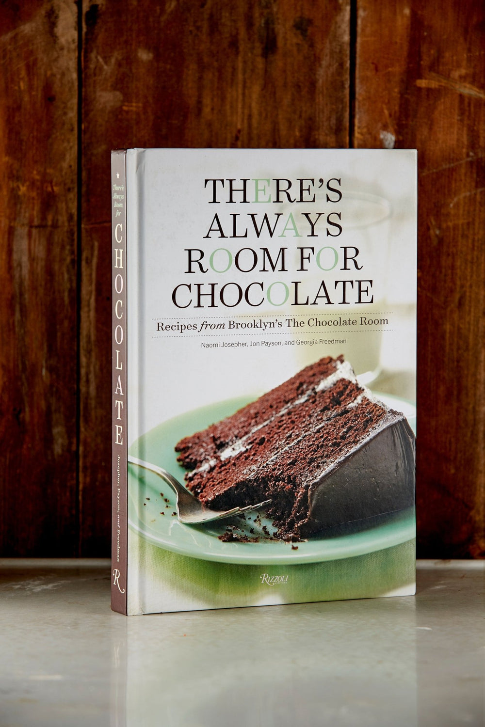 The Chocolate Room's There's Always Room for Chocolate cook book in front of a rustic wooden background