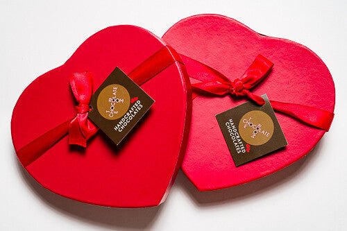 Red, heart shaped bonbon boxes wrapped with a red bow and branded The Chocolate Room